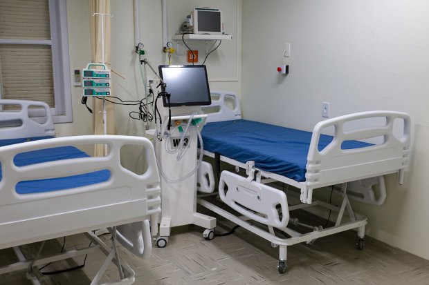 Leitos hospitalares vazios com equipamentos médicos em uma unidade de saúde.