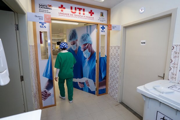 Profissional de saúde de roupa verde e touca azul com estrelas brancas entrando na porta da UTI