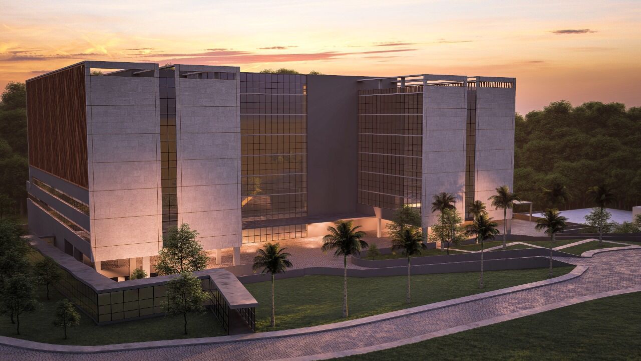 Renderização arquitetônica de um prédio moderno com fachada espelhada e estrutura simétrica, iluminado por luzes internas ao entardecer. O edifício está cercado por área verde com palmeiras e caminhos pavimentados, transmitindo sensação de inovação e integração com o ambiente.