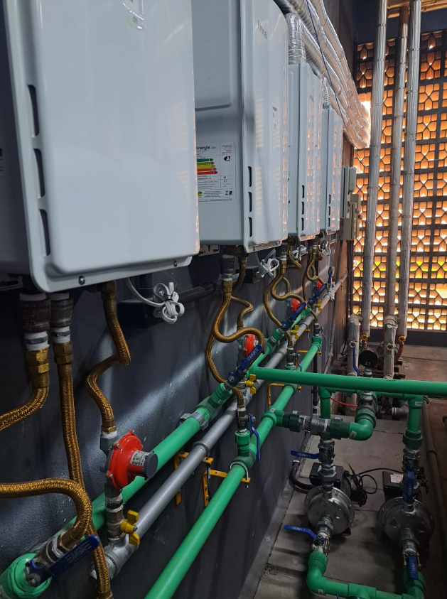 Sala técnica com aquecedores de água e tubulação verde e cinza, no Hospital Doutor Waldomiro Colautti.