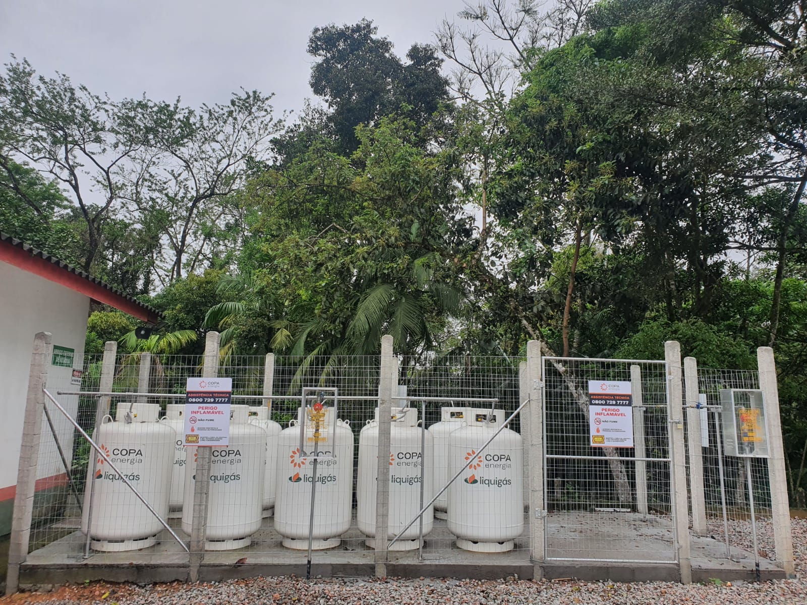Área cercada com cilindros brancos de gás da marca Copa Energia/Liquigás, ao ar livre, no Hospital Doutor Waldomiro Colautti.