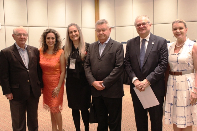 Grupo de autoridades e profissionais da saúde posando para foto durante o 67° Congresso de Secretarias Municipais de Saúde de Santa Catarina, em Joinville. O secretário de Estado da Saúde, Vicente Caropreso, está presente ao lado de outros participantes do evento, todos em trajes formais, em um ambiente de conferência.