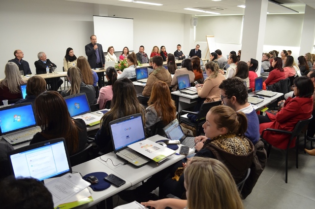 Auditório lotado com dezenas de profissionais da saúde assistem a uma mesa de autoridades durante capacitação.
