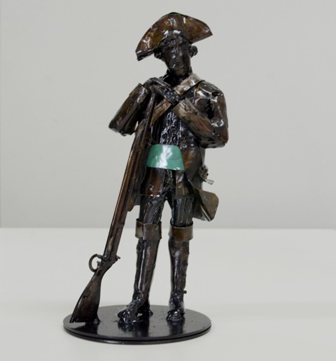 Estatueta Barriga Verde representando um soldado com uniforme histórico, segurando uma arma e com uma faixa verde atravessando a barriga.