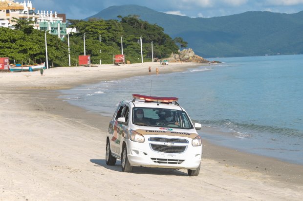 Viatura policial estacionada na areia da praia em Santa Catarina, durante operação de fiscalização do cumprimento das medidas restritivas contra a COVID-19.