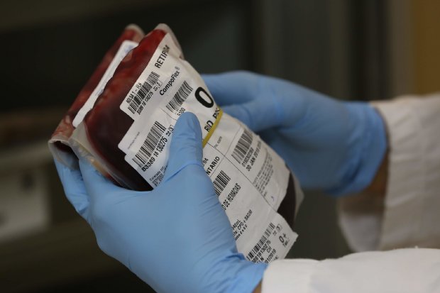 Mãos seguram dois sacos de sangue do tipo 'O'.