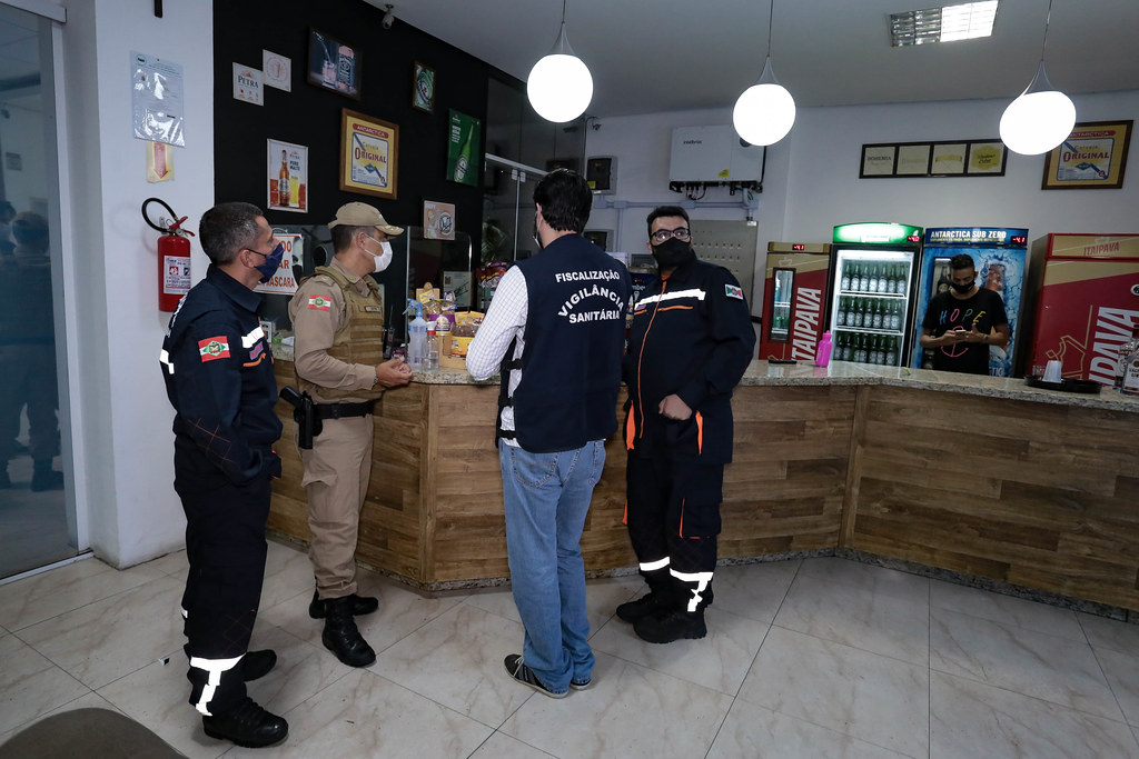 Equipe da vigilância sanitária de Santa Catarina realizando inspeção em loja, conferindo produtos e documentos durante fiscalização.