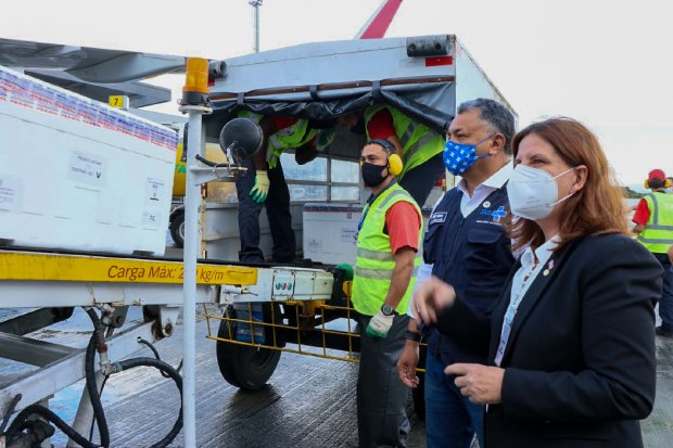 Governadora de Santa Catarina observando caixas térmicas com 144,7 mil doses de vacinas contra COVID-19 sendo carregadas em caminhão refrigerado, durante cerimônia de recebimento do novo lote.