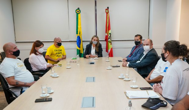 Governadora Daniela Reinehr em reunião com representantes do setor de eventos, em sala com bandeiras do Brasil e de Santa Catarina ao fundo, durante discussão sobre análise de protocolos pelo COES.