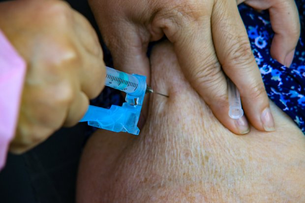 Profissional de saúde aplica dose da vacina Pfizer no braço de um paciente.