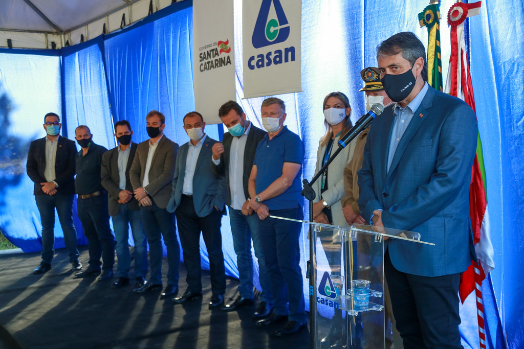 *"Grupo de autoridades posa no mesmo cenário institucional, composto pelas bandeiras do Brasil e de Santa Catarina ao fundo.