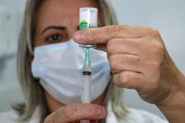Mulher loira preparando uma vacina segurando frasco e seringa