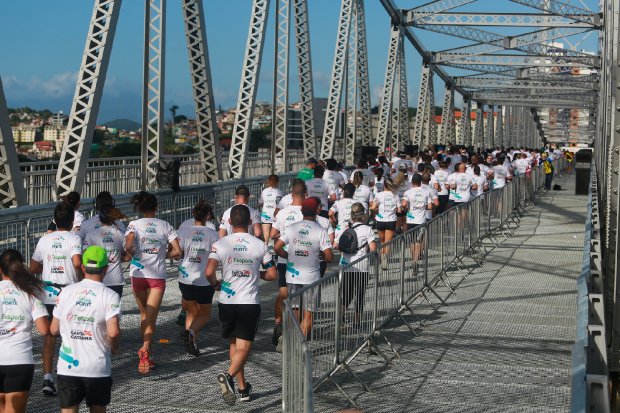 Várias pessoas correndo sobre a ponte Hercílio Luz