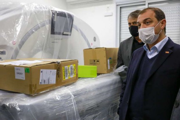 Governador de máscara, ao fundo tem outro homem com terno cinza