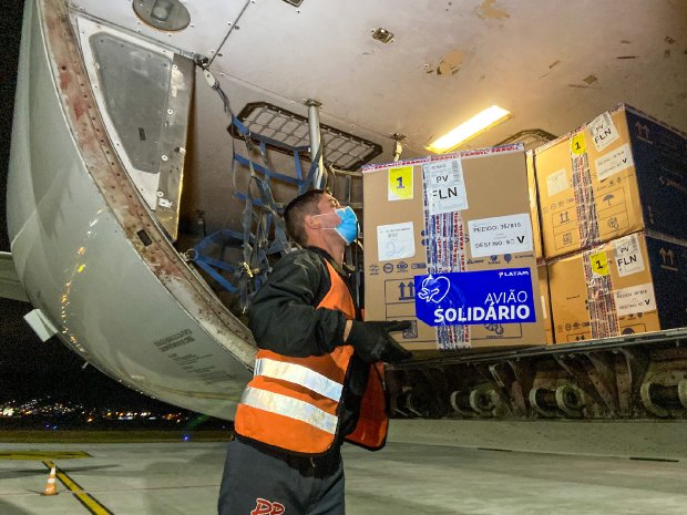 Homem de colete laranja descarregando caixas do avião