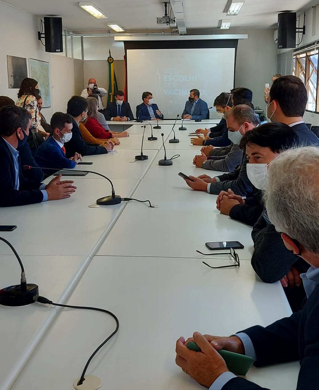 Diversas pessoas em mesas brancas fazendo uma reunião