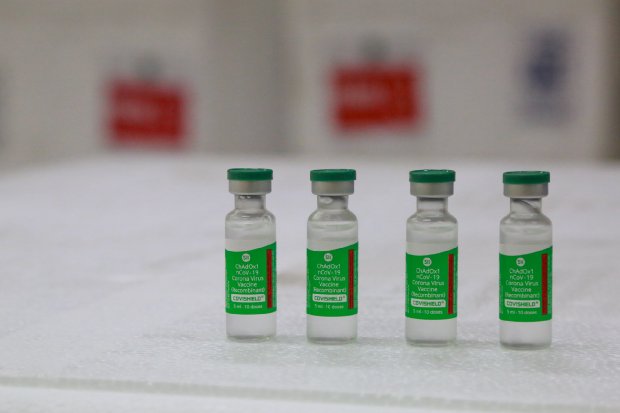 Quatro frascos de vidro com rótulo verde posicionados em uma mesa