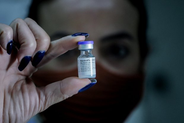 Mulher com unha azul e máscara segurando frasco