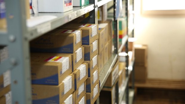 Estante repleta de caixas de medicamentos na cor bege.
