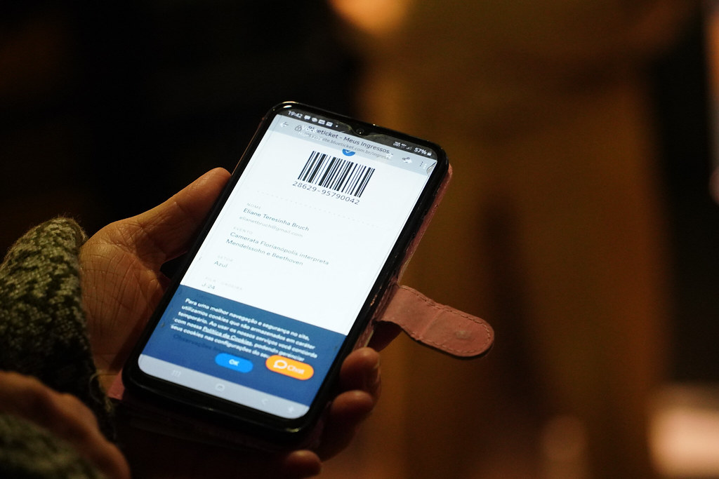 Mão segurando celular, na tela aparece um código de barra
