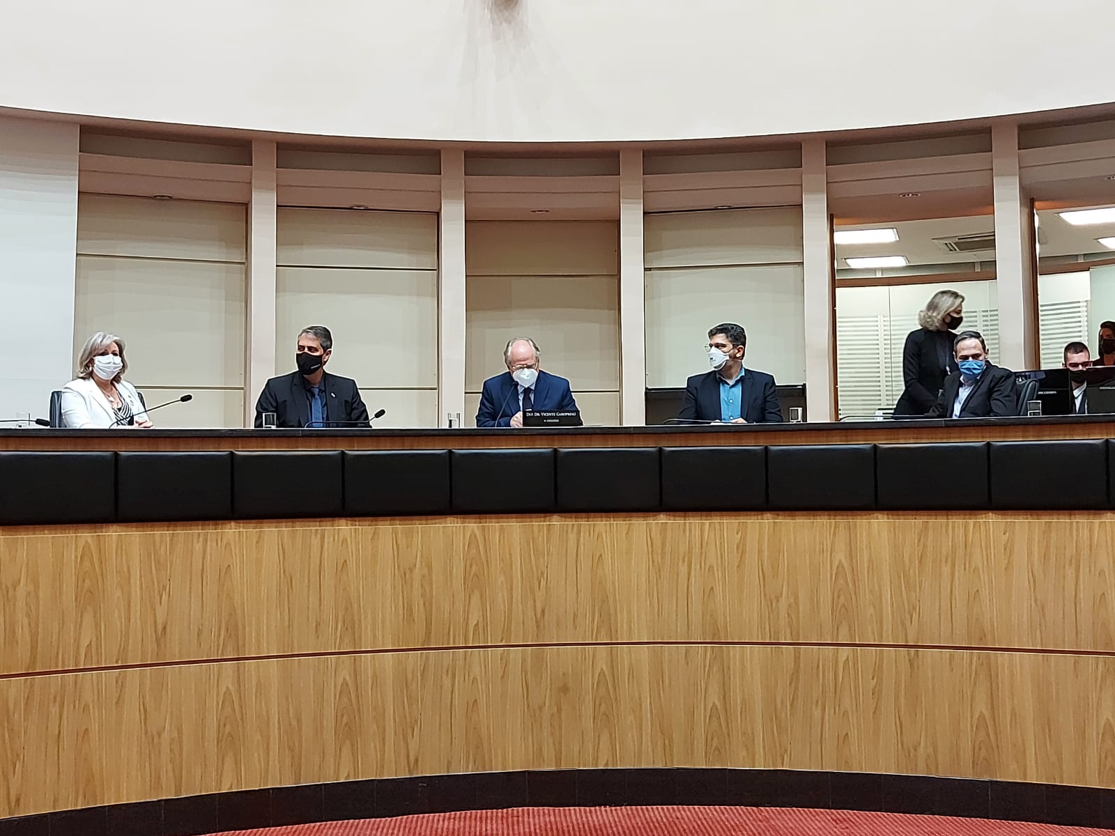 Diversas pessoas sentadas em uma grande mesa de madeira.