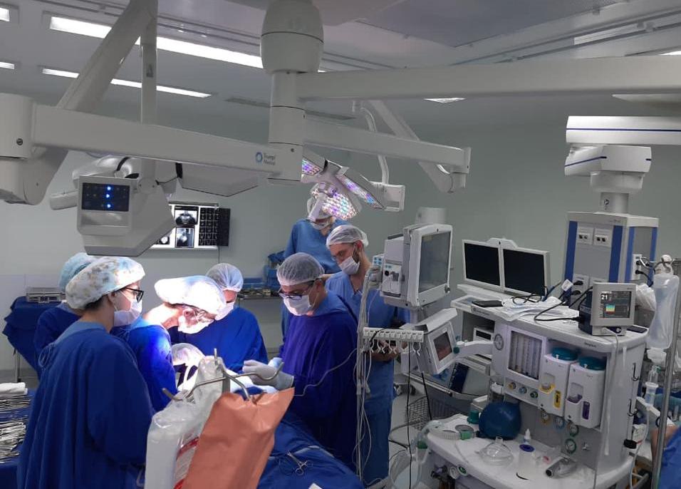 Equipe cirúrgica realizando procedimento de reconstrução mandibular em criança no Hospital Infantil Joana de Gusmão, em sala de cirurgia equipada com tecnologia avançada.