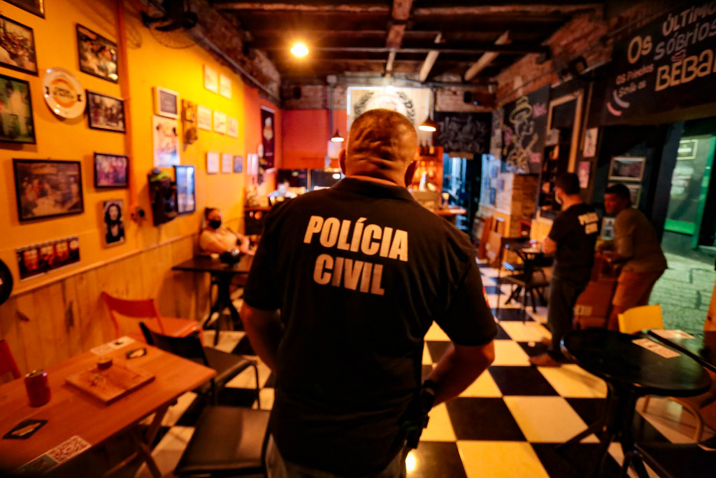 Agente da Polícia Civil realizando fiscalização dentro de estabelecimento comercial.