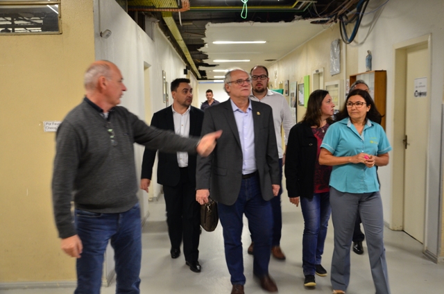 Secretário da Saúde Vicente Caropreso caminha por corredor do Hospital Maicé durante visita técnica, acompanhado por equipe técnica, servidores e profissionais da unidade hospitalar.