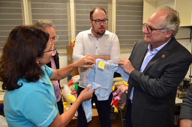 Secretário da Saúde Vicente Caropreso observa peça de roupa infantil confeccionada por voluntários do projeto Naninhas do Bem, durante visita ao Hospital Maicé, em Caçador.